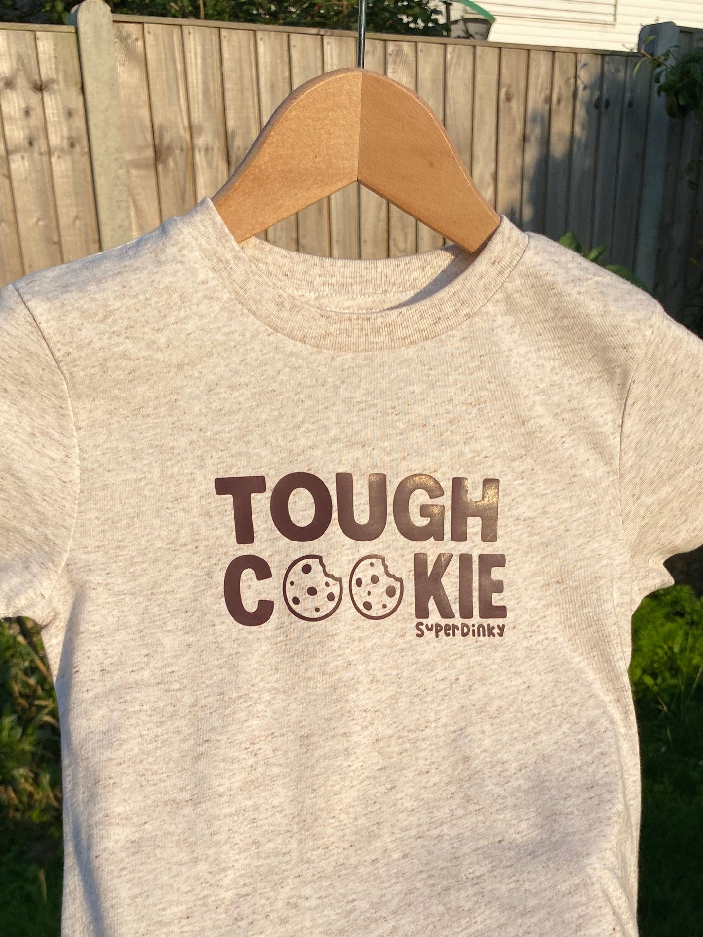 Gray t-shirt with 'Tough Cookie' text held by a person outdoors